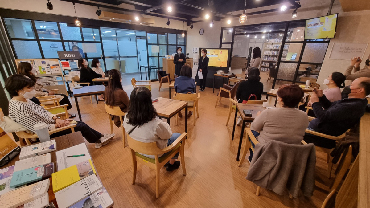 사회적거리두기 치침을 지켜 착석한 학생들의 뒷모습이 보고이고, 앞쪽 모니터를 등지고 교무처장과, 권량희 교수가 인사말을 나누는 모습 