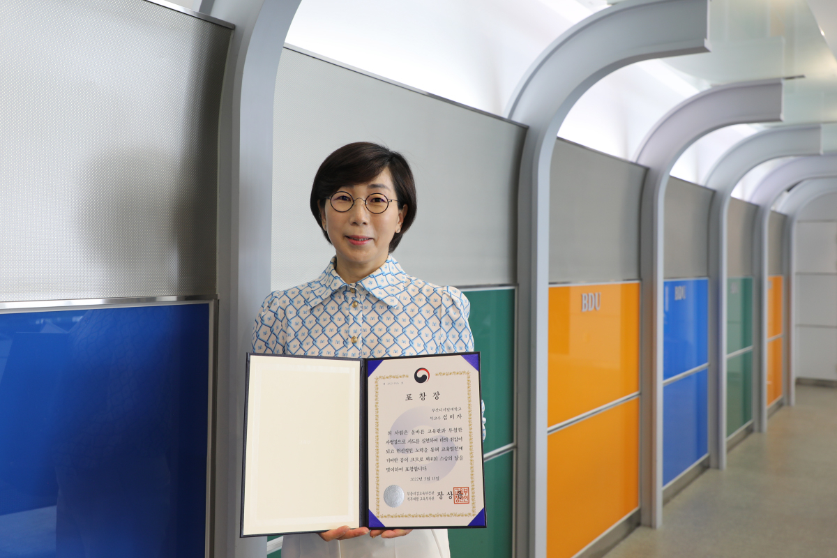 교육부장관 표창장을 펼쳐들고 기념사진을 찍은 심미자 교수(평생교육학과)